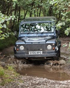 a black jeep driving through mud in the woods