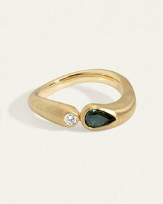 a gold ring with a green stone and two diamonds on the side, set against a white background