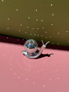 a shiny disco ball sitting on top of a metal object in the middle of a pink floor