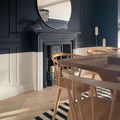 a dining room table and chairs in front of a fireplace with a mirror on the wall