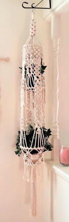 a white crocheted dream catcher hanging from a hook on the wall next to a candle