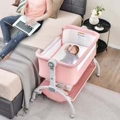 a woman laying on top of a bed next to a baby in a crib