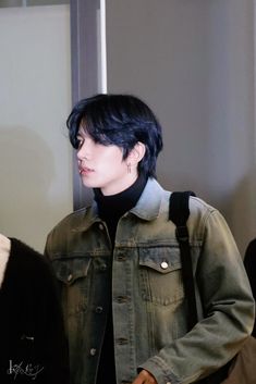 a man with black hair wearing a denim jacket