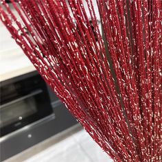 some red sticks are in a vase on the counter next to an oven and microwave