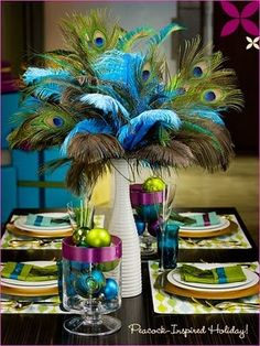 the table is decorated with peacock feathers and other decorations for an elegant dinner or party