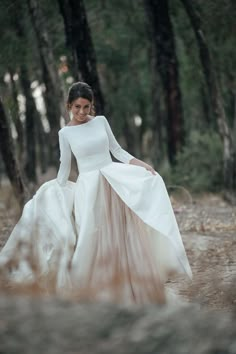 a woman in a white dress is walking through the woods