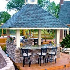 an outdoor bar with stools and tables in the middle of a deck area next to a gazebo