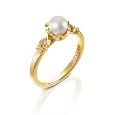 a gold ring with a pearl and diamonds on the side, in front of a white background