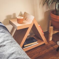 a small wooden table with a plant and books on it next to a couch in a living room