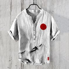 a shirt hanging on a wooden wall with a red circle painted on the front and side