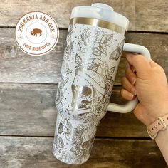 a hand holding a white coffee cup with an image of a bear and other animals on it