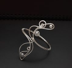 This arm cuff is versatile and perfect for a variety of occasions, always maintaining an elegant and spectacular appearance. Crafted from silver-plated wire, it features an exquisite wrapping of 8mm silver shell pearls. To ensure the perfect fit for your arm cuff, use a string or tape measure to determine the circumference of the area on your arm where you plan to wear the cuff. Wrap the string or tape around your arm, ensuring it sits comfortably but snugly, and note the measurement. If you req Elegant Silver Wire Wrapped Cuff Bracelet, Elegant Bangle Bracelets With Unique Design, Adjustable Silver Cuff Bracelet For Evening, Wire Arm Cuff, Upper Arm Cuff Bracelet, Silver Arm Cuff, Upper Arm Cuff, Arm Cuff Bracelet, Upper Arm Cuffs