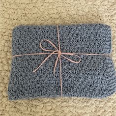 a blue crocheted blanket with a pink ribbon