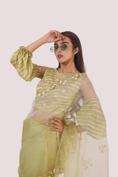 The stylish green organza saree with cold-shoulder balloon-sleeved blouse, embroidered with cut dana, off-white stripes blouse. Shop designer saris online in the USA from Pure Elegance. Disclaimer: The actual product may vary slightly from the image. These are custom orders, hence expect slight variation in color and placement of the motif or buta. ESTIMATED DELIVERYBecause this is a custom order, it would take about 4 weeks from the date of purchase. RETURN POLICYThis product is a custom order and cannot be returned or exchanged. Green Chanderi Blouse With Sheer Dupatta, Summer Organza Sharara With Sheer Dupatta, Summer Semi-stitched Pre-draped Saree For Designer Wear, Pista Green Organza Blouse Piece For Festivals, Green Zari Work Saree For Summer, Green Saree With Zari Work For Summer, Pista Green Chanderi Blouse With Dupatta, Semi-stitched Pista Green Organza Blouse Piece, Festive Organza Salwar Kameez With Unstitched Blouse