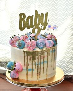 a white cake with pink, blue and gold frosting on top that says baby