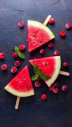 slices of watermelon with mint and raspberries on a black slate surface