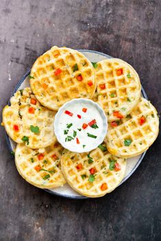 several waffles on a plate with a small bowl of ranch dressing in the middle