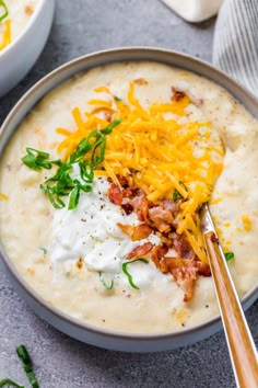 a bowl of potato soup with cheese and bacon on top, topped with sour cream