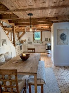 a wooden table sitting in the middle of a living room next to a kitchen area