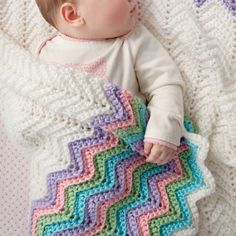 a baby laying on top of a blanket covered in crocheted blankets and holding it's head