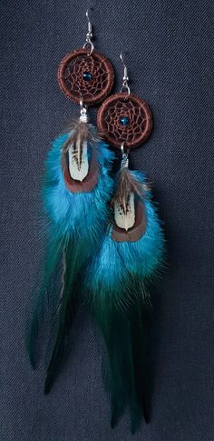 a pair of earrings with feathers hanging from it's ear hooks on a black background