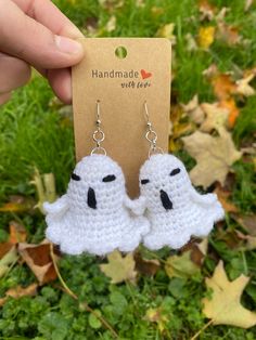 a pair of white crocheted ghost earrings with black eyes on them, hanging from a card