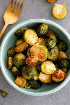 a bowl filled with brussel sprouts next to a fork