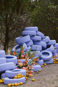 a bunch of blue tires stacked on top of each other in front of some flowers