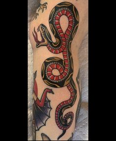 a man with a tattoo on his arm has a red and black snake in the shape of a bat