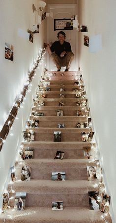 a man sitting on top of a set of stairs covered in pictures and christmas lights