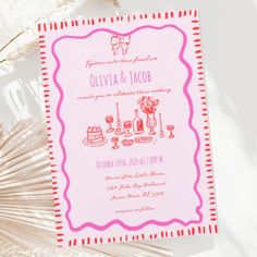 a pink and red wedding card sitting on top of a table