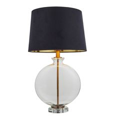 a glass table lamp with a black shade on the top and gold trimmings