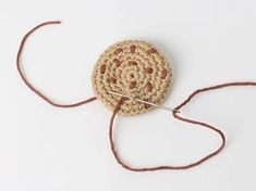 a crocheted round object on a white surface with a needle in the middle