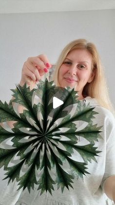 a woman holding up a green and white paper fan