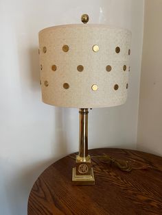 a lamp that is sitting on top of a wooden table next to a white wall