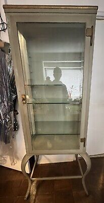 an old metal and glass display cabinet on casteors, with the door open to reveal a man's shadow