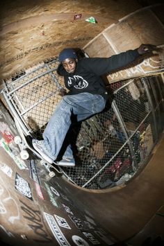 a man riding a skateboard up the side of a metal fence in a cage