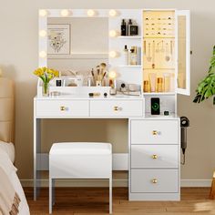 a white vanity with lights on it and a stool in front of the mirror that is open