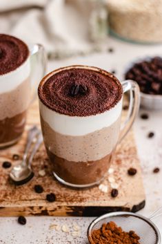 two cups filled with chocolate and coffee on top of a cutting board