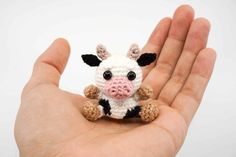 a hand holding a small crocheted cow in it's palm