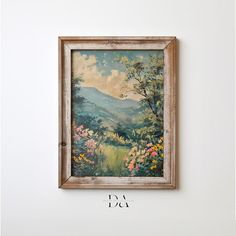 a painting hanging on the wall above a wooden frame with an image of mountains and flowers