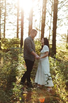 a man and woman holding hands in the woods