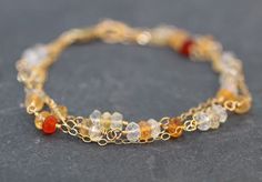 Prized for its fiery color, this mexican fire opal bracelet is fiery and bright.  Named for its flashes of light, the fire opal stones range from white to yellow and orange red.  The vivid ombre opals are delicately wire wrapped in gold and combined with gold filled chain in an asymmetrical design.  Each stone has beautiful faceting which reflects the light.  Available in 6-7 or 7-8 inch version. Opal is a birthstone for October and also a suggested gemstone gift for a 14th anniversary.   Choose 14th Anniversary, Mexican Fire Opal, Semi Precious Jewelry, Garden Jewelry, Opal Bracelet, October Birthstone, Asymmetrical Design, Nature Bracelets, Precious Jewelry