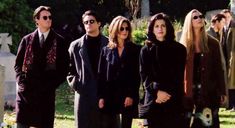 a group of people standing next to each other in front of headstones on the ground