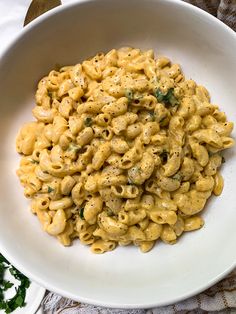 a white bowl filled with macaroni and cheese on top of a table cloth