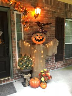 a decorated front porch with pumpkins and lights