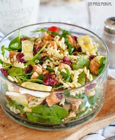 a glass bowl filled with salad on top of a wooden cutting board