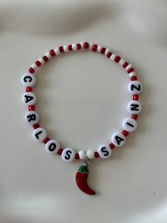 a red and white beaded bracelet with a pepper charm