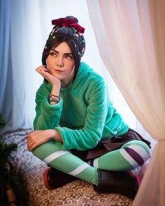 a woman sitting on top of a bed wearing tights and a green sweater with polka dots