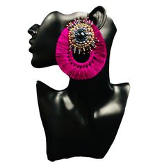 a black mannequin head with a pair of pink earrings on top of it